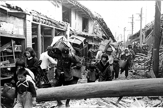 爆撃で倒壊した家から住民が避難