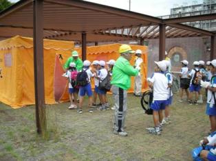 防災福祉コミュニティが煙体験ハウスを使って小学生に煙の怖さを教えている写真